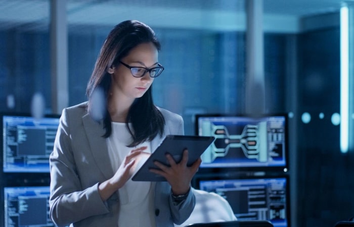 A woman in glasses is looking at her tablet.